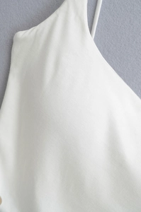 Detailed macro view of white ribbed fabric texture and fine shoulder strap stitching