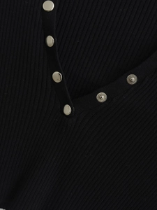 Detail of the V-neckline with silver metal snap buttons on a black ribbed knit cardigan