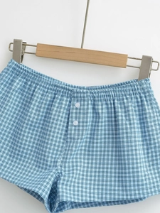 Detail of blue plaid shorts featuring elastic waistband and white button decoration