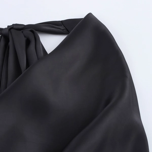 Close-up of black satin halter top featuring a delicate neck tie and soft pleated texture