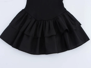 Detail of black tiered ruffle hem with V-shaped seam on sleeveless halter dress