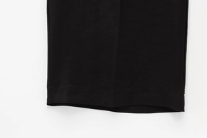 Dettaglio dell'orlo dei pantaloni neri a gamba larga con trama fine e piega stirata