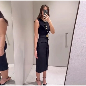 Détails d'une robe midi noire sans manches avec boutons dorés et poches à la taille