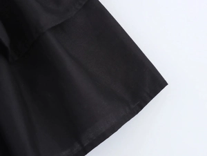 Detailed close-up showing the layered hem design and neat stitching on black halter dress