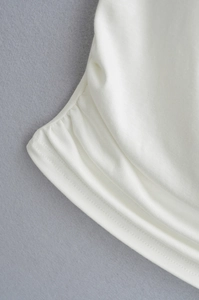 Close-up of white ribbed fabric with detailed lettuce trim and stretchy texture detail