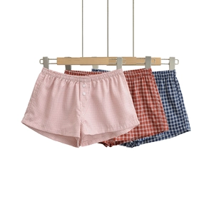 Detailed view of three plaid boxer shorts featuring elastic waist and button fly closures
