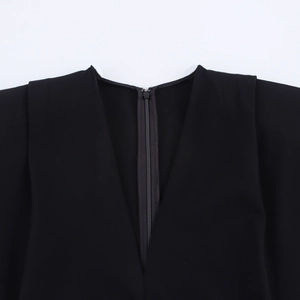 Detail of V-neckline with hidden zipper and padded shoulders on a black midi dress