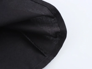 Detailed close-up of edge stitching and texture on a black halter neck maxi dress