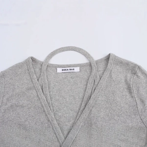 Top in maglia grigia con scollo a V, trama a costine e dettaglio anello decorativo
