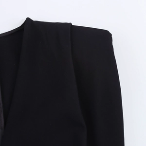 Close-up of structured shoulder and textured black twill fabric of the midi dress