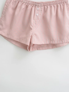 Detail of pink and white gingham shorts featuring elastic waistband and button accents