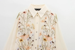 Detail of floral printed cream shirt showing pointed collar and pearl buttons close-up