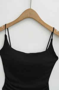 Close-up of slim shoulder straps and side ruched detailing on the black camisole top