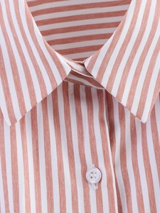 Detail of the orange striped shirt collar and translucent button texture on the fabric
