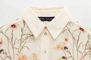 Detail shot of the floral print collar and shell buttons on this light beige shirt