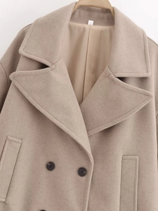 Détail d'un manteau en laine beige avec boutons croisés classiques et texture de revers fine