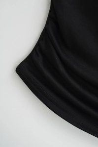 Close-up of black ribbed knit fabric with ruched side details and seamless stitching