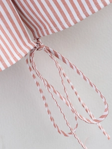 Detail of red and white striped shirt fabric with a neatly knotted drawstring waist tie