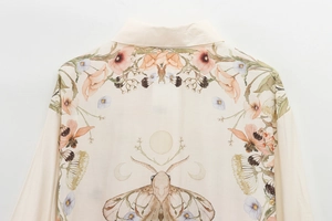 Close-up of vintage watercolor floral and moth print on off-white silk-textured shirt