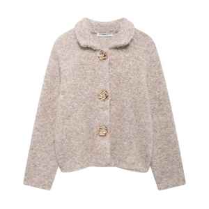 Dettaglio ravvicinato di un cardigan in maglia soffice con tre bottoni dorati a forma di fiore