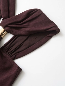 Close-up of wine red knit fabric with elegant gold metal ring buckle and pleated texture