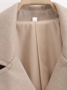 Détail du col d'un manteau en laine beige avec revers large et doublure lisse