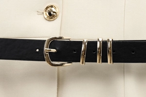 Gros plan d'une ceinture en cuir noir avec boucle dorée sur un gilet beige