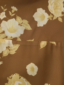 Detailed close-up of brown floral chiffon fabric with delicate yellow flower patterns
