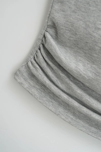 Detailed macro view of heather grey knit fabric featuring side ruched seams and stitching