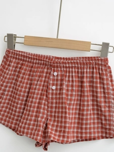Close-up of red plaid shorts featuring an elastic waistband and white decorative buttons