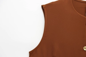 Détail d'une robe sans manches caramel avec bouton doré et texture de tissage fin
