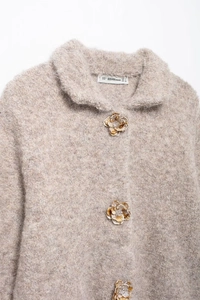 Dettaglio del cardigan in ecopelliccia con trama materica e bottoni a forma di fiore