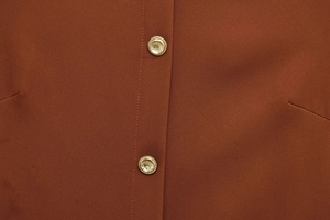 Détail de la robe midi caramel montrant le tissu texturé et les boutons dorés