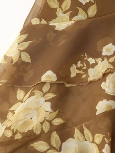 Detail of floral chiffon fabric with delicate gold ruffled edges and semi-transparent texture