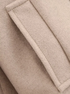 Gros plan sur la texture en laine d'une veste beige avec détails de couture de poche