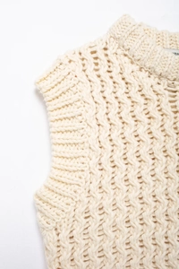 Détail du gilet en maille torsadée beige montrant la texture et les finitions