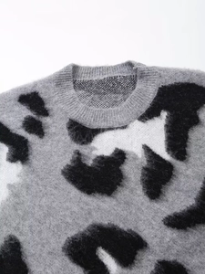 Detail shot of crew neck sweater with black and white abstract cow print knit pattern