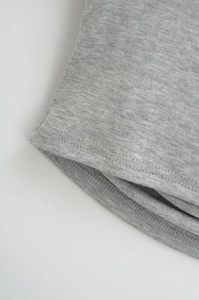 Detailed close-up of light grey knit fabric featuring precise hem stitching and texture