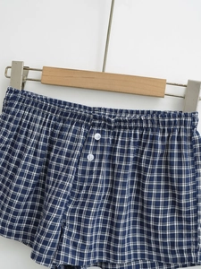 Detail view of blue and white checkered shorts with elastic waist and button accents