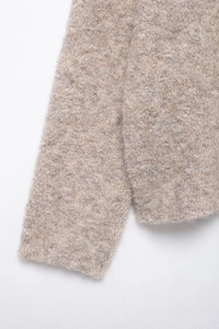 Dettaglio ravvicinato del cardigan in maglia beige con morbida trama in finta pelliccia