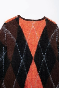 Detail of soft mohair knit sweater with argyle pattern in brown, black and orange colors