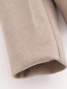 Détail macro du poignet de veste en laine avoine avec couture précise et doublure
