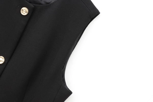 Gros plan sur le tissu du gilet noir sans manches avec boutons métalliques dorés