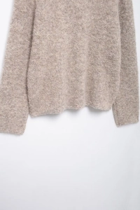 Dettaglio del cardigan in maglia avena con morbida texture in pelliccia sintetica