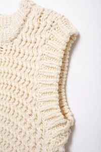 Gros plan du gilet en maille crème avec texture épaisse et détails côtelés au col