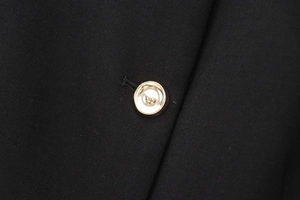 Détail macro d'un bouton métallique doré de qualité sur un gilet noir ajusté