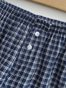 Detail view of blue and white plaid shorts featuring an elastic waist and two white buttons