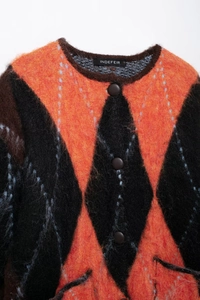 Close-up of fluffy argyle knit cardigan featuring orange and black diamond pattern and buttons