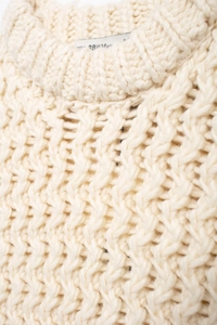 Détail de gilet en maille crème montrant le motif ondulé et la texture de qualité