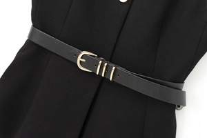 Détail d'un vêtement noir avec ceinture en similicuir et boucle ronde dorée